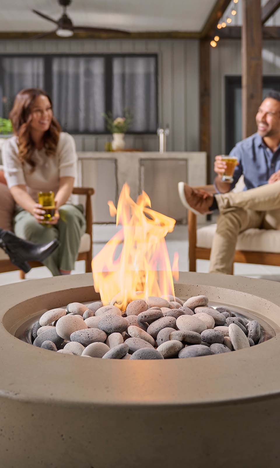 Man and woman laughing behind a firepit