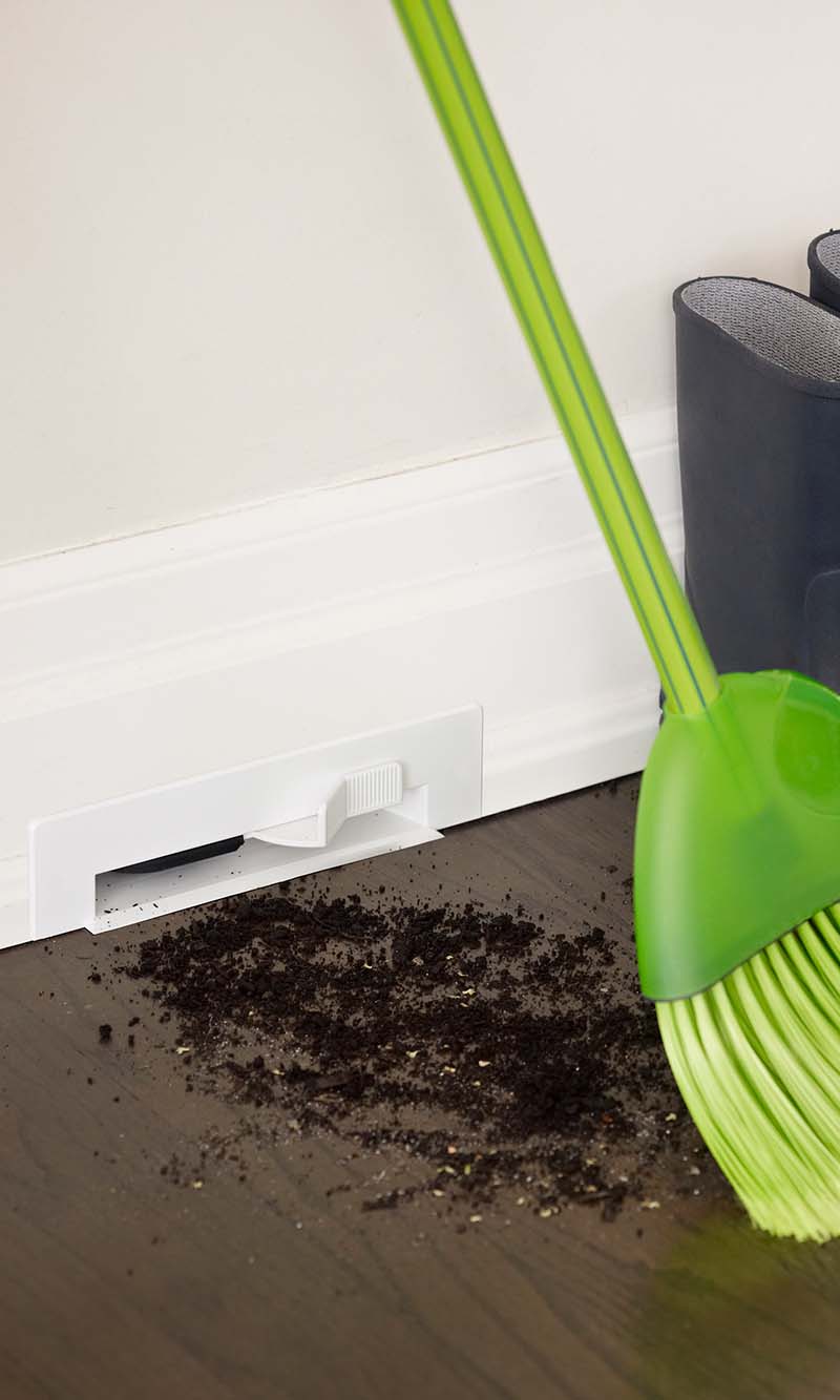 Broom sweeping dirt into a wall peice