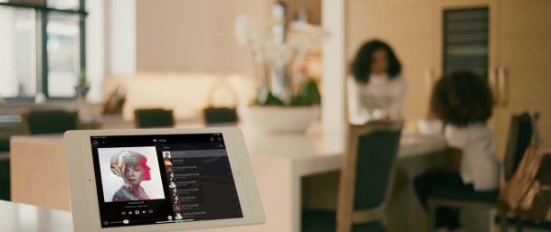 Woman and Child in a kitchen with an ipad featuring a Control4 interface