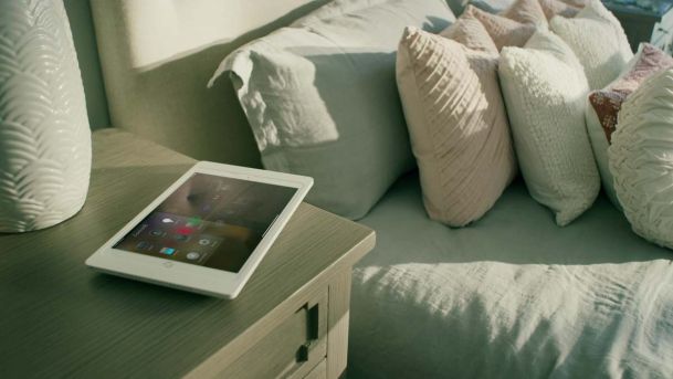 ipad on a nightstand next to a bed with control4 interface
